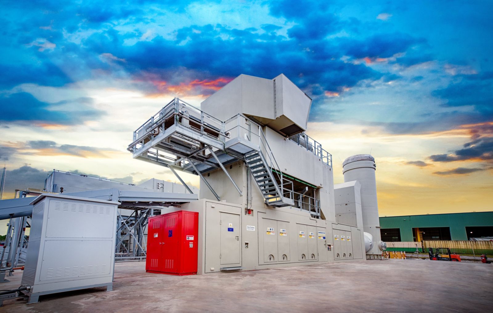 真實照片：一座灰色的Solar Turbines工業燃氣渦輪機組廠房，附樓梯與平台，機身面板印有Solar Turbines字樣，攝於黃昏